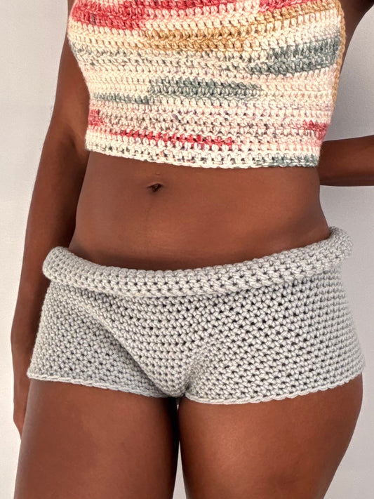 Person wearing a patterned crochet top and shorts on a plain background